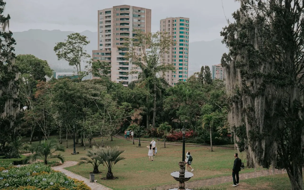 Parc verdoyant à Medellín, pelouse, arbres et fontaine, avec la ville et les montagnes en arrière-plan